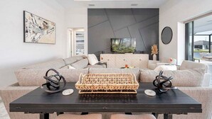 A modern living room with a sectional sofa, a black coffee table, and a large flat-screen TV.