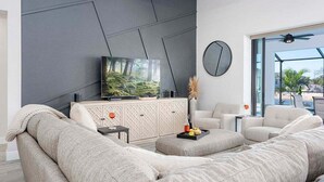 A modern living room with a large flat-screen TV, a sofa, and a coffee table.