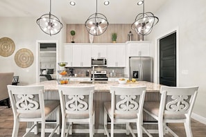 Una cocina moderna con armarios blancos, una isla central e iluminación colgante.
