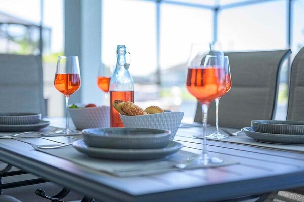 Una mesa preparada para una comida, con copas de vino, una botella y un bol de pan.