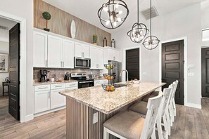 A modern kitchen with white cabinetry, a granite countertop, and a central island with seating.