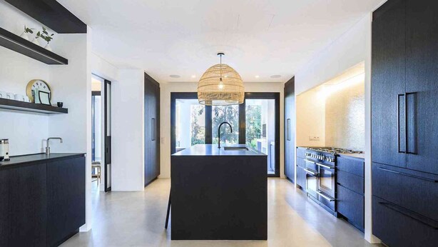 A modern kitchen with a central island, dark cabinetry, and a hanging light fixture. - 5 Star Villa Magnolia – Luxury Lakefront Retreat (Algarve)