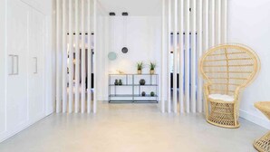 A modern interior with white walls, a glass shelf with decorative items, and a wicker chair. - 5 Star Villa Magnolia – Luxury Lakefront Retreat (Algarve)