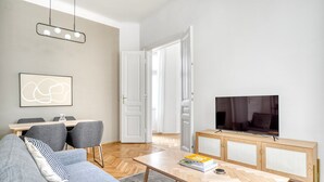 Un salon moderne comprenant un canapé, une table basse, un téléviseur et un coin repas avec des chaises et une table.