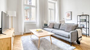 Un salon moderne avec un canapé gris, une table basse en bois et un téléviseur posé sur un meuble en bois.