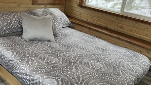 A wooden cabin bedroom with a large bed, two windows, and a view of trees. - Osprey Lake Caboose beside the Kettle Valley Railway and 2 mins from Osprey Lake (Summerland)