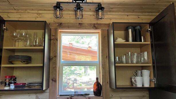 A wooden cabin kitchen with a window, shelves with glassware, and a coffee maker. - Osprey Lake Caboose beside the Kettle Valley Railway and 2 mins from Osprey Lake (Summerland)