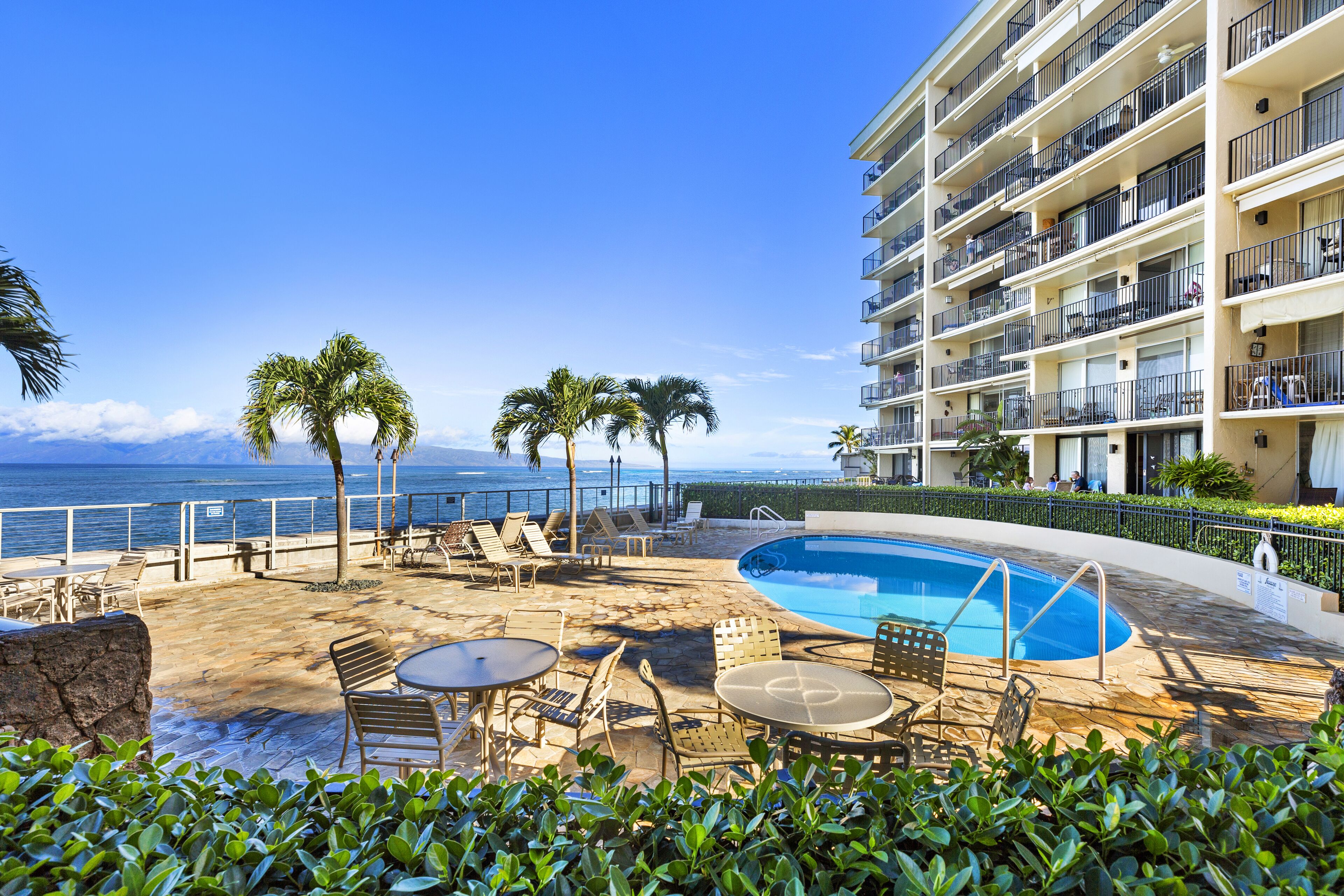 A poolside area with lounge chairs, a small pool, and a view of the ocean.