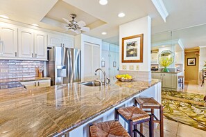 A modern kitchen with granite countertops, stainless steel appliances, and a large island with bar stools.
