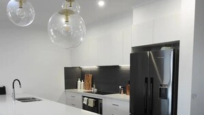 A modern kitchen with a central island, stainless steel appliances, and pendant lighting.