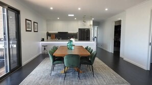 A modern dining area with a wooden table, green upholstered chairs, and a grey rug.