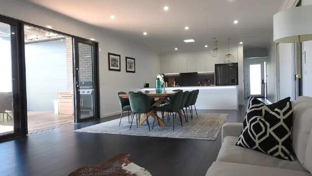 A modern living room with a dining area, a sofa, and a rug.