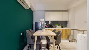 Cocina compacta con microondas, lavabo y un pequeño comedor con mesa y sillas.