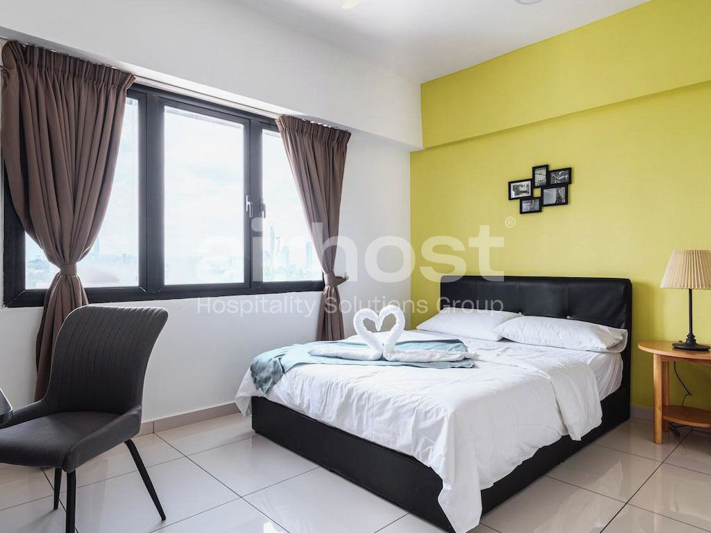 Une chambre d’hôtel avec un lit, une chaise, une table de chevet et une fenêtre avec des rideaux.