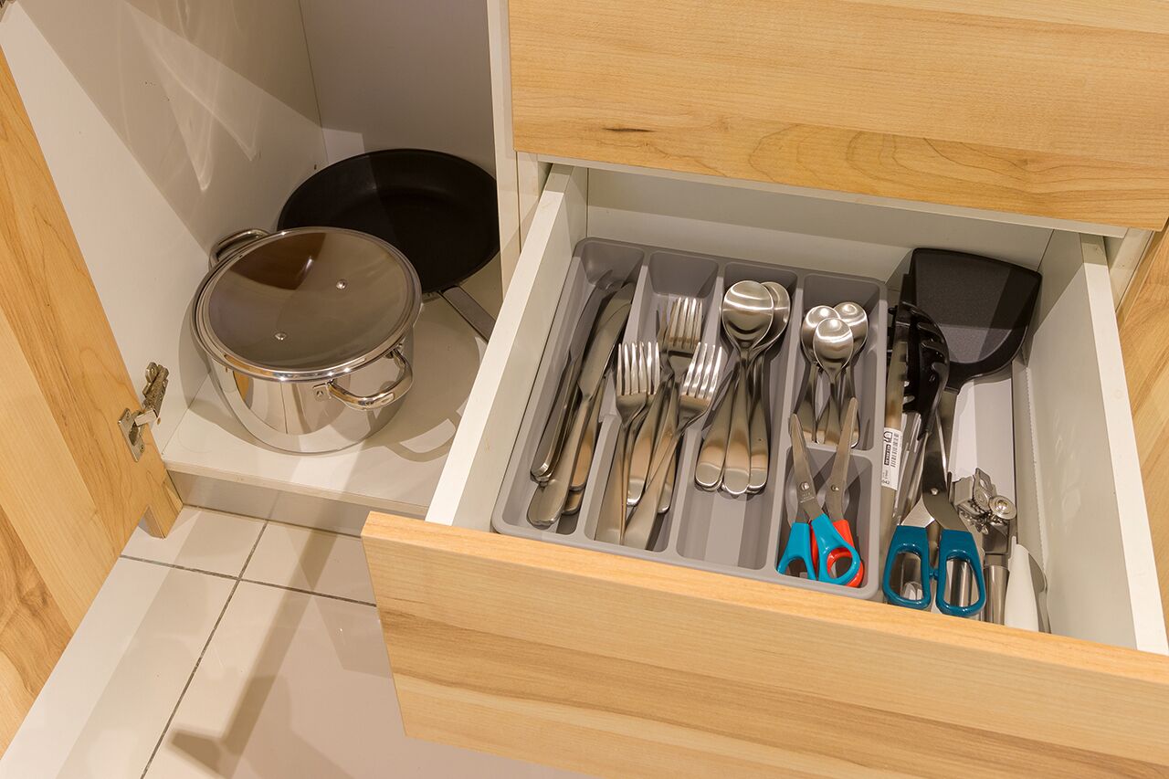 Un cajón con utensilios de cocina, como tenedores, cuchillos y una espátula.