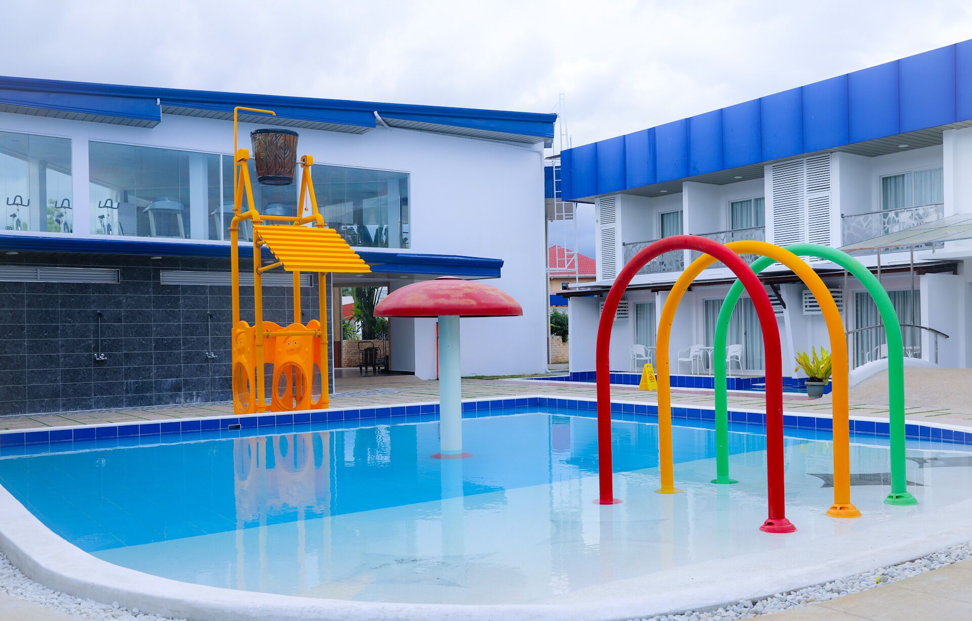 A swimming pool with colorful arch structures and a water slide.