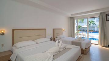 A hotel room with two beds, a view of a swimming pool, and a balcony with outdoor furniture.