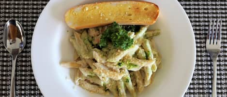 A plate of pasta with a piece of bread on a checkered tablecloth.