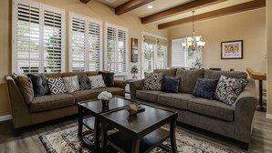 A living room with two sofas, a coffee table, and a chandelier. - Single story Luxurious 1 BR 1 BA Kitchen Living Resort Pools Gym (La Quinta)