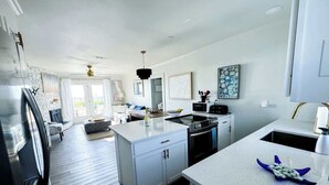 Una cocina moderna con una isla central, un área de comedor con sofá y vista al salón.