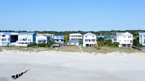Propiedad frente a la playa con varias edificaciones blancas, una playa arenosa y olas oceánicas.