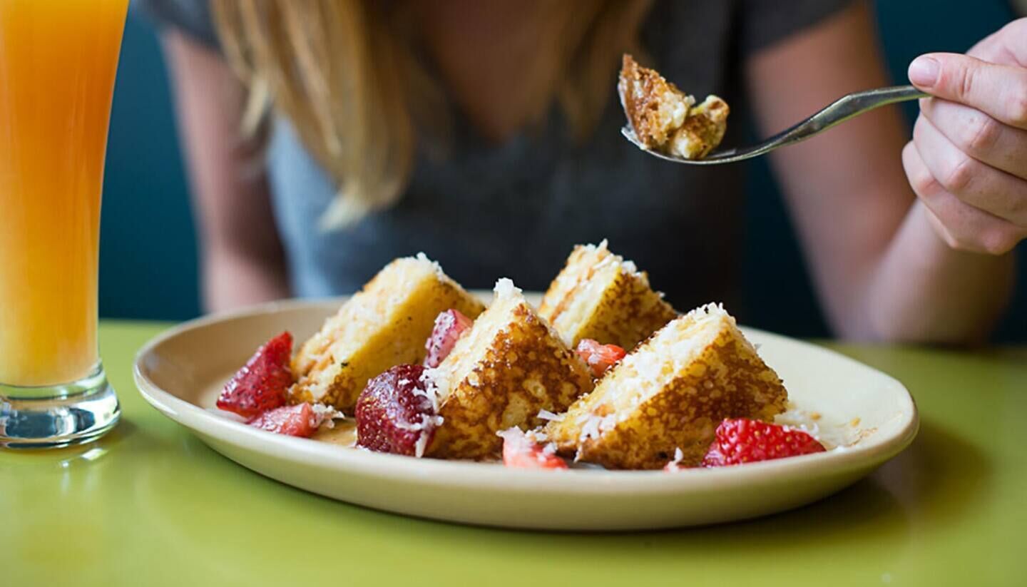 A plate of layered cake with strawberries and a glass of orange juice.