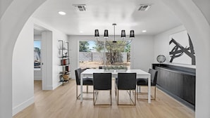A modern dining area with a white table, black chairs, and a chandelier. - NEW 1 Min Walk DT Gilbert - 4 Bedroom Retreat (Gilbert)