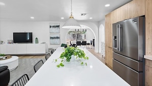 A modern kitchen with a central island, stainless steel appliances, and a dining area with a white table and chairs. - NEW 1 Min Walk DT Gilbert - 4 Bedroom Retreat (Gilbert)
