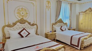 Une chambre d’hôtel luxueuse, dotée de deux lits richement décorés, d’un grand miroir et d’un lustre classique.