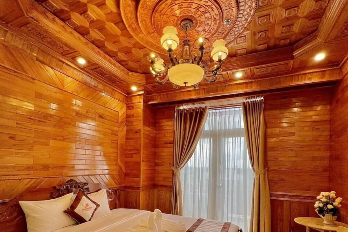 A wooden-paneled room with a bed, a chandelier, and a small table with chairs.
