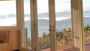 Une pièce dotée de grandes portes-fenêtres coulissantes donnant sur un paysage magnifique, avec des montagnes et un lac en toile de fond.
