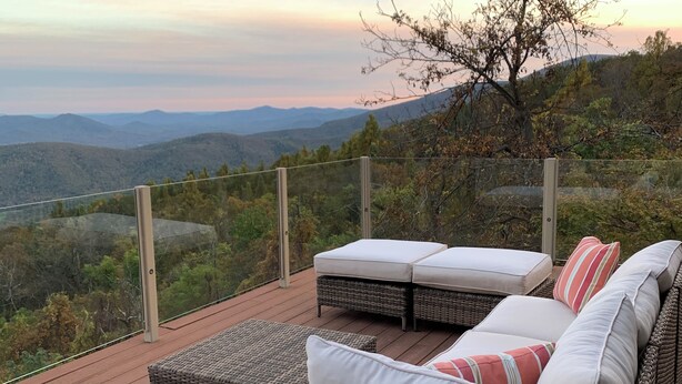 Une terrasse dotée de meubles en osier et de coussins, offrant une vue sur un paysage montagneux.