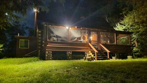A cabin with a large window, a staircase, and a well-lit exterior.