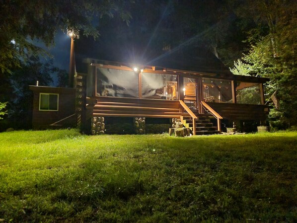 A cabin with a large window, a staircase, and a well-lit exterior.