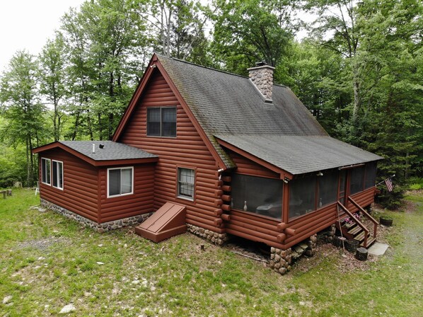 Eine Blockhütte mit Schornstein, einer Veranda und einem kleinen Anbau.