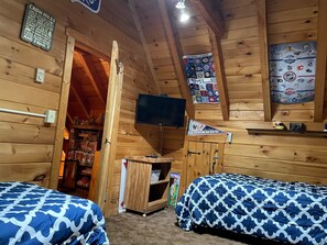 Ein Blockhaus-Zimmer mit zwei Betten, einem an der Wand befestigten Fernseher und verschiedenen Sportmemorabilien.