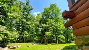 A view of a forested area with a stone wall and wooden beams, likely part of a building's exterior.