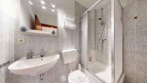 A modern bathroom with a glass-enclosed shower, a white sink, and a toilet.