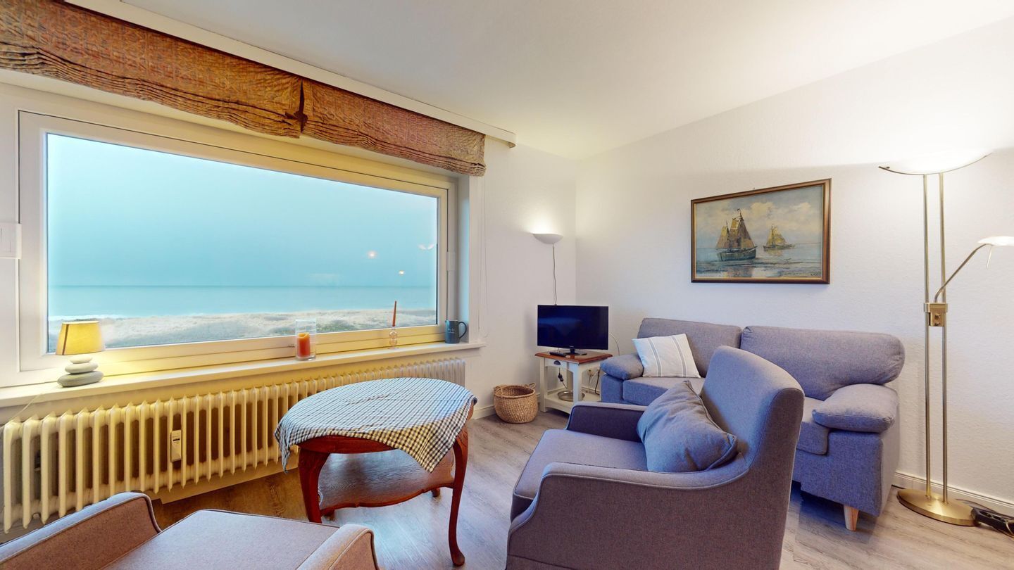 A living room with a large window, a sofa, a table, a TV, and a painting on the wall.