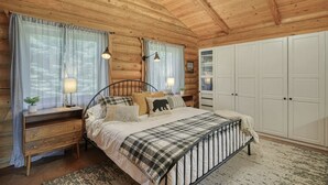 Un dormitorio de cabaña de troncos con cama, mesitas de noche, un armario y un ventilador de techo.