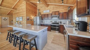 Una cocina espaciosa con paredes de madera y una isla grande, equipada con electrodomésticos modernos y taburetes de bar.