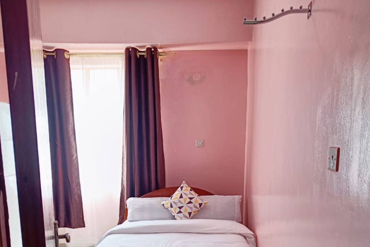A bedroom with a bed, a window with curtains, and a door.
