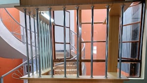 Un estrado de madera con barandillas metálicas, una escalera con paredes anaranjadas y un suelo de baldosas.