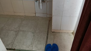 Un baño con lavamanos, paredes de azulejos y un par de pantuflas azules en el suelo.