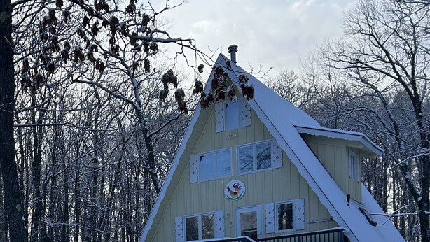 A large, multi-story wooden building with a steep roof, surrounded by snow-covered trees.