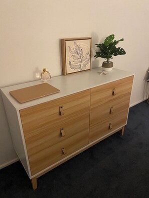 A wooden dresser with a white top, drawers, and a small plant on top. - Quiet relaxing home close to beach, lake at your doorstep. (Swanhaven)