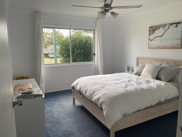 Un dormitorio con cama, un escritorio con ordenador portátil y una ventana con cortinas.