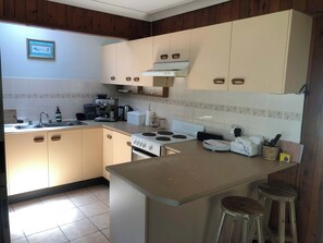 Una cocina con estufa, pileta y muebles de madera.