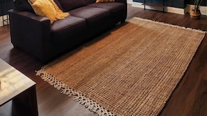 A living room with a dark brown sofa, a woven rug, and a ceiling fan.