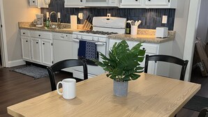 A modern kitchen with white cabinetry, a built-in microwave, and a dining area with a wooden table and chairs.